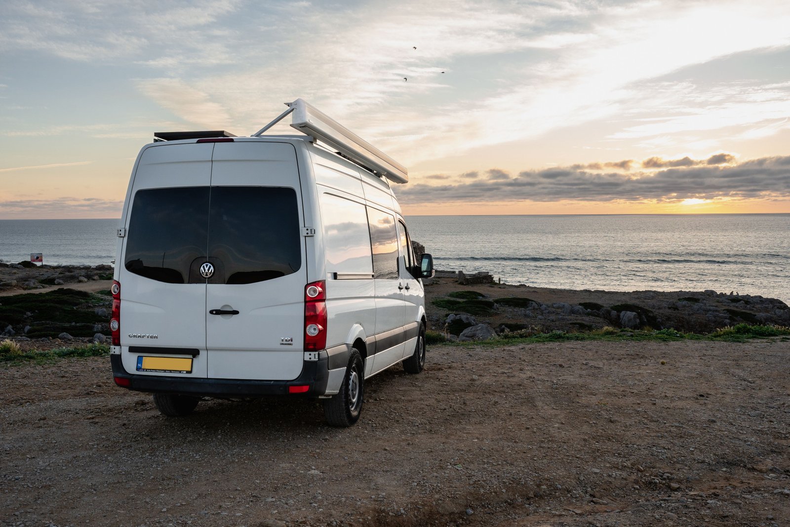 Adelaar Campers buscamper bij de oceaan tijdens zonsondergang